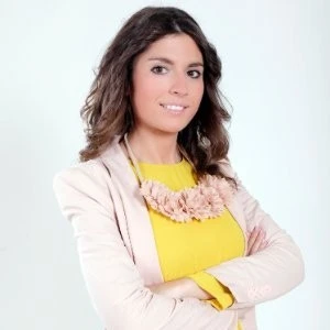 Smiling businesswoman with crossed arms wearing a light jacket and yellow top